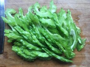 苦瓜洗净，从中间切开，挖去中间的瓤，再斜切成薄片；