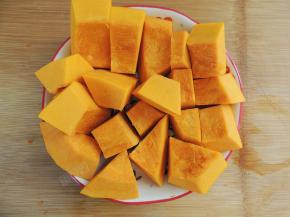 将南瓜清洗干净，然后切掉外面坚硬的皮，挖掉里面的南瓜瓤和南瓜籽，改刀切成块状，装入盘中。