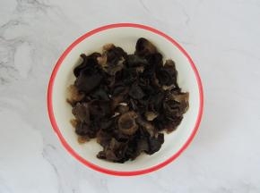 将泡发的木耳清洗干净，撕成小朵，去掉根部，然后均匀的铺在碗底。