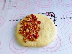 醒好的面团用擀面杖擀圆饼，再饼皮的1/2处撒上红枣碎，如图。