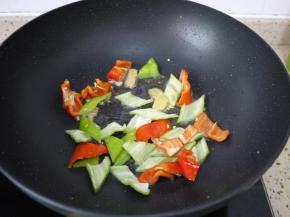 锅中留底油，把大蒜和姜片放入锅里煸炒出香味，然后把青红辣椒放入锅中，翻炒到断生。