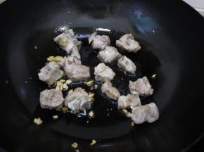 热锅凉油，把大蒜和姜放入锅中煸炒出香味。然后把排骨倒入锅中，翻炒至两面金黄。