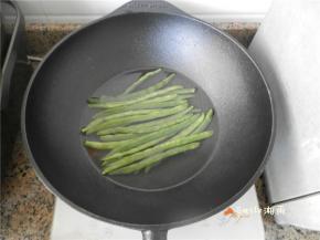 铁锅放电磁炉上烧开水，淋点油，放四季豆煮5分钟，捞出来用冷水洗（这样可保持四季豆的爽口）。
