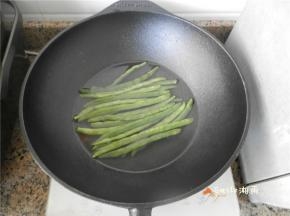 铁锅放电磁炉上烧开水，淋点油，放四季豆煮5分钟，捞出来用冷水洗（这样可保持四季豆的爽口）。
