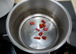 制作香辣油。把干辣椒切成小段，放在锅中小火煸一下，锅中不用放油，干煸就可以，大概煸炒一分钟，注意不要把辣椒炒糊。