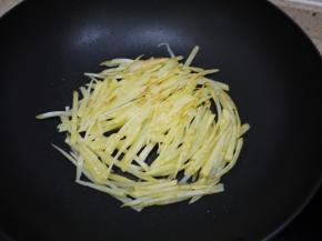 热锅凉油，先放一半的土豆丝在锅里面，尽量铺成一个圆形，不能铺太厚，用中火煎土豆。把土豆饼的一面煎成金黄色即可翻面。