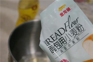 然后将金龙鱼面包用小麦粉配在里面，刚好500克的量。然后再加入酵母，厨师机选择二档模式，揉至15分钟的样子，再加入玉米油继续揉至面团光滑出膜。