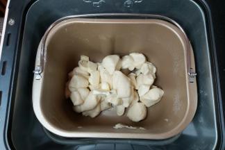 当程序进行到15分钟的时候，暂停机器，取出面团，把面团切成小块再放入桶内，同时加入软化好的黄油。