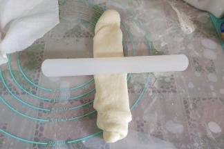 取一个擀卷的面团，再次擀成长舌状，不要来回擀，在中间固定，然后用擀面杖朝两边拉长，长度要比之前长一些。