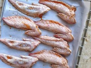 烤制前沥一下多余的调料汁，  将鸡翅放在铺了油纸的烤盘上