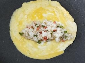 底下的蛋液有点凝固以后就放入适量的米饭。米饭的位置就放在鸡蛋的1/3处。