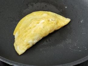 然后借助锅铲把另外一端的鸡蛋饼翻过来合在一起。