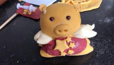 再用红面团做一个围裙，围在小金猪的腰下面，用五角星装饰