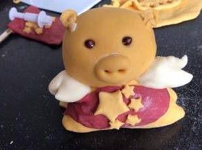 再用红面团做一个围裙，围在小金猪的腰下面，用五角星装饰