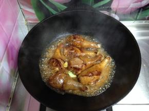 炒锅底部放入葱段、姜片后放入鸡腿，倒入腌鸡腿时的汤汁和啤酒