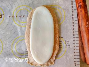 醒发后的面团上下擀长，翻面后底边压薄，将麻薯分成3份，1份擀开后比面团稍小一点，铺在面团上。