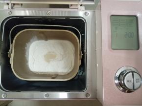 往面包桶依次倒入牛奶、蛋液，对角倒糖和盐，加入奶粉和面粉，在面粉顶端加上酵母，把面包桶放入东菱JD08面包机里，选择和面程序13分钟，不同型号的面包机和面时间会有所不同
