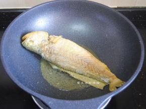 一面煎好后，翻另一面继续煎到金黄，放上姜片，裹了淀粉的鱼真的很耐翻哦。