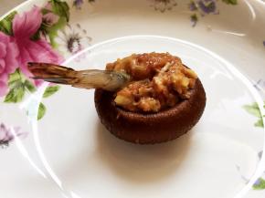 把虾头位置放入香菇伞中，加入一茶匙肉馅，虾的尾部留出来。