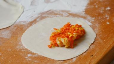 将一勺胡萝卜馅放在饺子皮的三分之一处