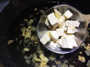 锅中加入三汤碗（一个人量的汤碗），包括浸泡黄花菜的水，倒入胡辣汤内的菜包，加入豆腐丁。
