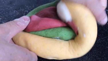 把黄面团压大点包住绿、红、白面团，摞在一起揉压卷成卷