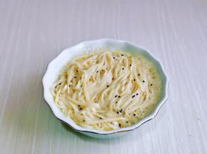 再加入淋干水分的面条，用筷子翻拌均匀，使面条均匀裹上蛋奶液。