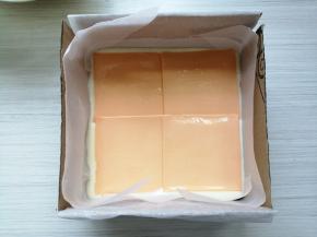 倒入2/3的蛋糕糊，在桌面上震几下，震出气泡，在上面铺上四块芝士片