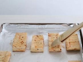 烤盘铺上锡纸，摆入豆干，表面刷一层油。