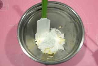 将糖粉倒入软化好的黄油中。黄油需要软化到用刮刀可以轻易抹开。夏天室温软化，冬天的话可以放烤箱，开发酵档进行软化。