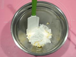 将糖粉倒入软化好的黄油中。黄油需要软化到用刮刀可以轻易抹开。夏天室温软化，冬天的话可以放烤箱，开发酵档进行软化。