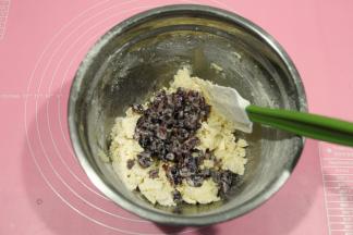 然后用刮刀，切拌，往盆边按压，拌到几乎无干粉。将浸泡在牛奶中的果干，沥干水分放入。（可以稍微挤干一点，不然面团湿度太大，不好整形）