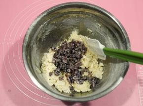 然后用刮刀，切拌，往盆边按压，拌到几乎无干粉。将浸泡在牛奶中的果干，沥干水分放入。（可以稍微挤干一点，不然面团湿度太大，不好整形）