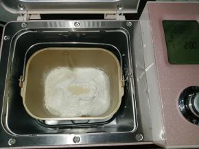 往面包桶依次倒入冰水、蛋液，对角倒糖和盐，再倒入奶粉和面粉，在面粉顶端加入酵母，把面包桶放入到东菱JD08面包机里，选择面包机的和面程序13分钟