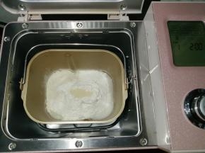 往面包桶依次倒入冰水、蛋液，对角倒糖和盐，再倒入奶粉和面粉，在面粉顶端加入酵母，把面包桶放入到东菱JD08面包机里，选择面包机的和面程序13分钟