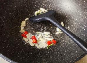 热锅倒油，升温后放入蒜瓣片和小米辣，爆香。