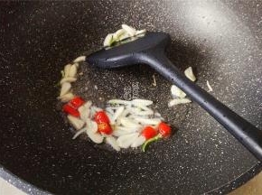 热锅倒油，升温后放入蒜瓣片和小米辣，爆香。