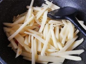 把土豆条捞起沥干，倒入锅中翻炒下，炒制微微变色。