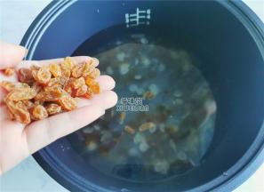 把泡发的水倒掉，挑出杂质，倒入电饭煲内胆中，倒入适量清水，放入葡萄干。