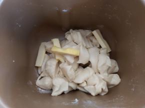 取出面团切成小块或者用剪刀剪成小块，同时把软化好的黄油也一并放入面包桶内，然后再放回面包机。