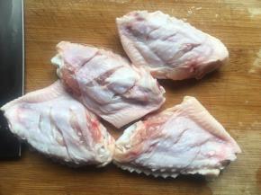 将鸡翅放入清水中浸泡半小时左右，洗净后用厨房纸擦干表面多余水分，然后在鸡翅的正反面划几刀以方便入味；