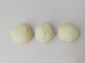 面团放在垫子上，挤出面团里面的空气，分成3份，揉圆盖上保鲜膜放在室温下醒发15分钟。