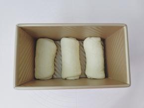 擀好的面团从上而下卷起来放入模具。