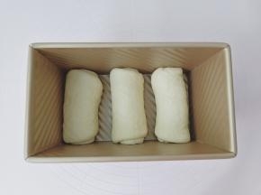 擀好的面团从上而下卷起来放入模具。