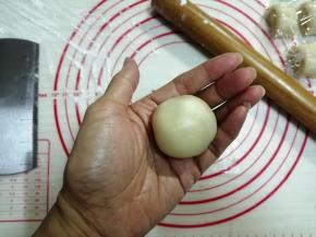 右手虎口位置放饼皮，左手按压着馅料，一边转一边将饼皮向上收口