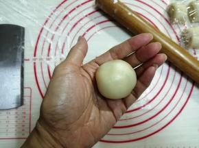 右手虎口位置放饼皮，左手按压着馅料，一边转一边将饼皮向上收口