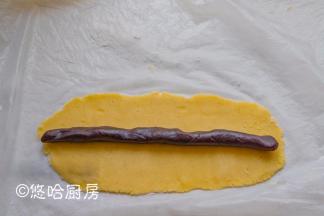 冷藏后的面团切成3条，一条80克左右。一块面团垫着保鲜膜、撒一点干粉，用擀面杖擀开成长方形，中间放一条红豆沙，豆沙在60克左右。