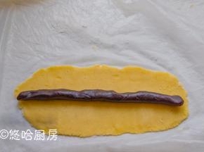 冷藏后的面团切成3条，一条80克左右。一块面团垫着保鲜膜、撒一点干粉，用擀面杖擀开成长方形，中间放一条红豆沙，豆沙在60克左右。