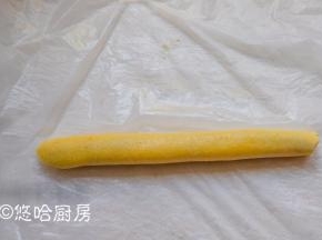 借助保鲜膜将面团包起红豆沙，卷紧。