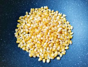 炒锅内倒适量的食用油烧热，下入玉米粒翻炒均匀。